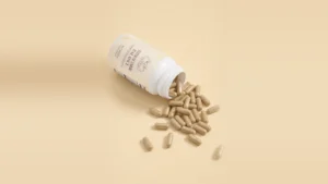 Thyrafemme Balance review: open bottle of Thyrafemme Balance thyroid support capsules for women spilling onto a cream background
