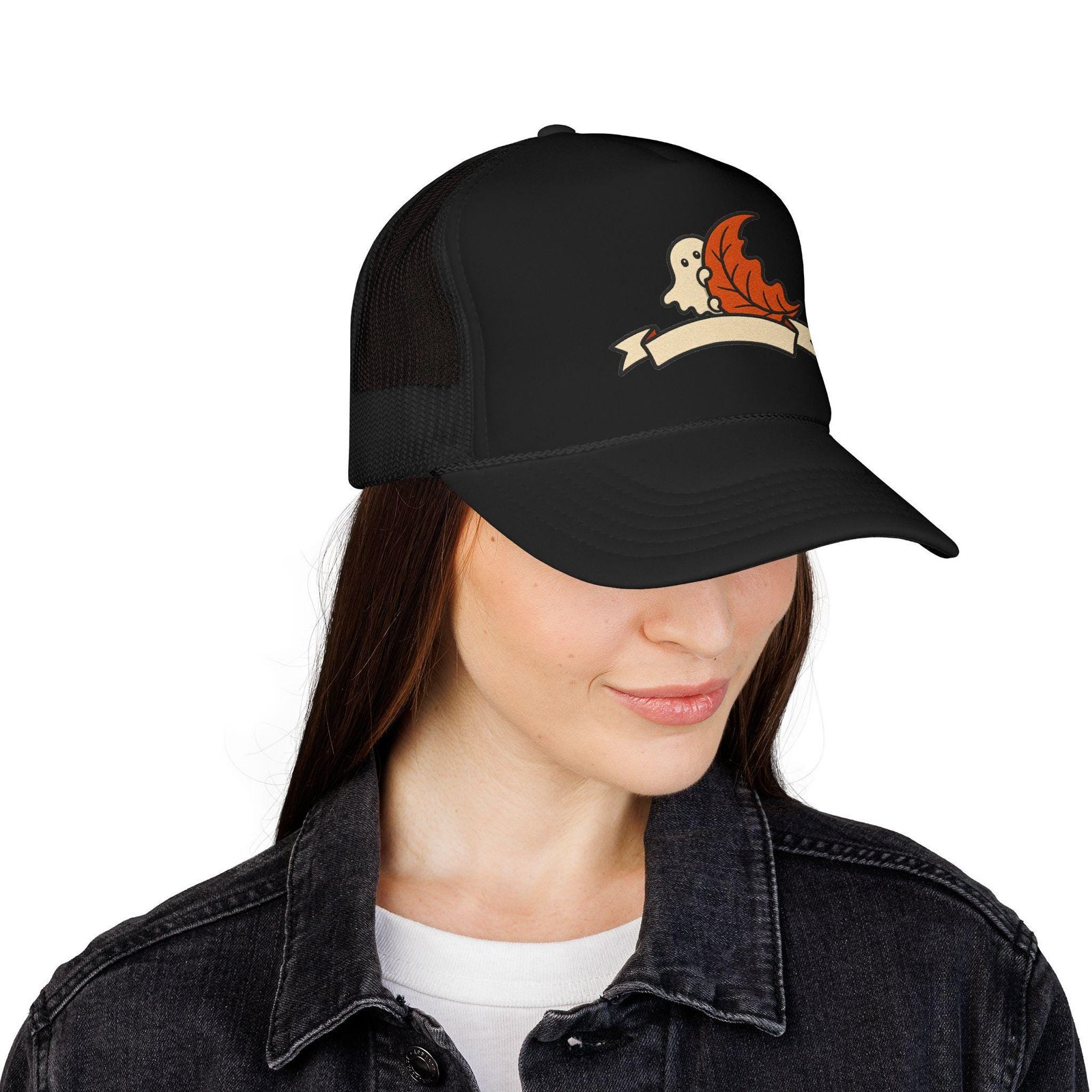 Woman in a denim jacket wearing the black ghost and autumn leaf trucker cap